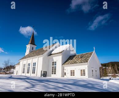 Hattfjelldal-Kirche, Norwegen. Sehr sonniger Tag, viel Schnee, sehr tiefblauer Himmel und fast keine Wolken, Seitenansicht Stockfoto