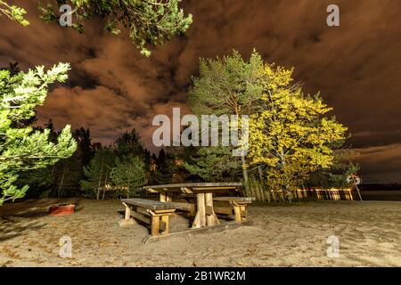 Einsamer schwedischer Strand mit Lagerplatz und Holztischbänken im Freien in der Herbstnacht, Provinz Vasterbotten Stockfoto