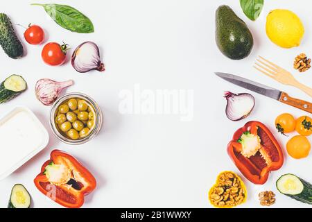 Flat Lay Food Anordnung von biologischem Gemüse, Fetakäse, Nüssen und Grüns. Zutaten für griechischen Salat auf weißem Hintergrund, Draufsicht mit leerem sp Stockfoto