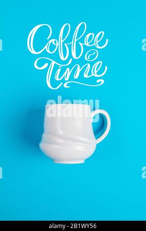 Blauer Kaffeebecher auf blauem Hintergrund mit dem Text Kaffeezeit Stockfoto