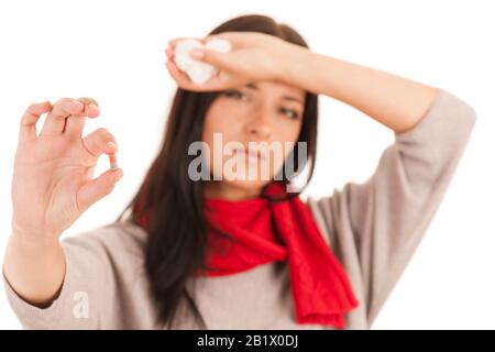 Die kranke Frau hält eine Pille in der Hand, isoliert über dem weißen Hintergrund. Stockfoto