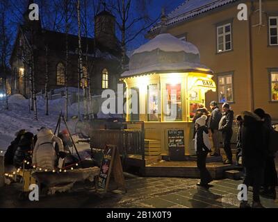 Kunden stehen an der kleinsten Bar des Rocket Kiosk Norwegens Schlange, die an einem kalten Winterabend warme Getränke in Tromso verkauft Stockfoto