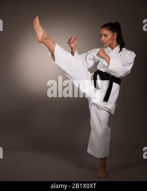 Frau in weißem Kimono tritt hoch in die Luft - ein karäisches Kampfkunstmädchen Stockfoto