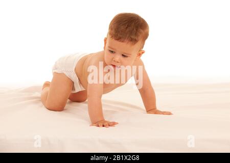 Hapy Baby Junge beim Spielen auf dem Bett isoliert über weiß Stockfoto