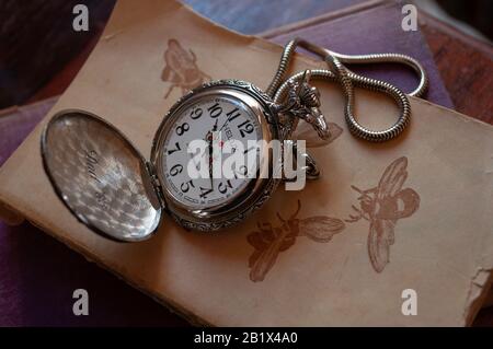 Silberne Taschenuhr mit "83" auf alten Büchern Stockfoto