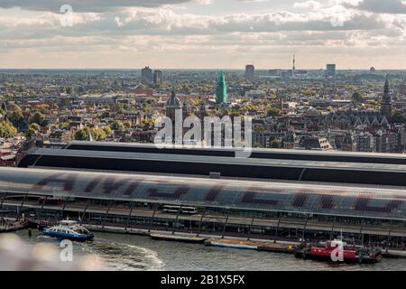 Hoher Aussichtspunkt auf die historische Innenstadt der niederländischen Hauptstadt mit Fährkai und Bahnhof im Vordergrund und breiterem Stadtbild im Rücken Stockfoto