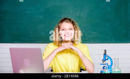 Wissenschaftslabor, Lehrer für Wissenschaftler im Schullabor, Biologieexperiment, Mädchen im Klassenraum mit Computer, glücklicher Student mit Mikroskop und Becher. Notizen über die Forschungsergebnisse aus der Chemie machen. Stockfoto