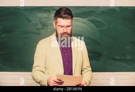 Theorie erklären. College und High School. Vorbereitung auf den Test. Lehrer bärtiger Mann hält Dokumente Hintergrund des Schwarzen Bretts. Unterlagen für Lehrer. Schulleiter. Anspruchsvoller Lehrer. Dozent im Klassenzimmer. Stockfoto