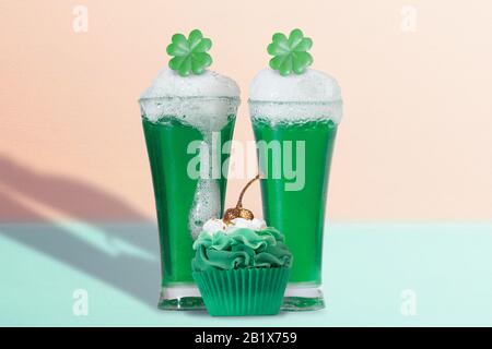 Zwei Pints grünes Bier mit Shamrock Topper und Green Cupcake mit Gold, Glitter Cherry Stockfoto