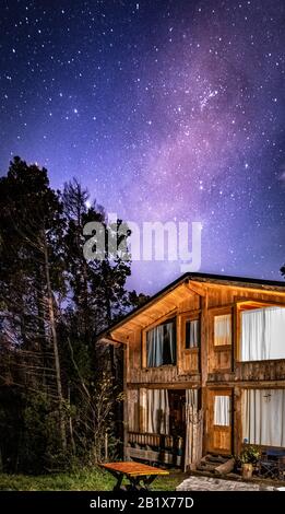 Bariloche, ARGENTINIEN, 19. JUNI 2019: Außenansicht einer gemütlichen und entspannenden Holzhütte im Wald mit einem wundervollen Sternenhimmel Stockfoto