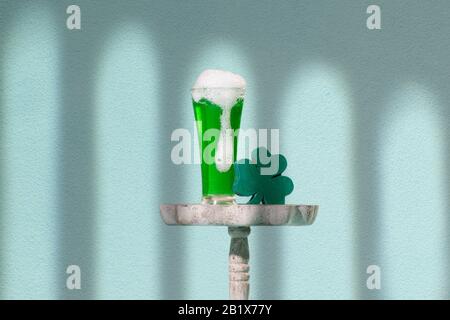 Schäumendes Pint Grünbier auf einer schäbigen, schicken Tischplatte mit Holzschamrock, Kleeblattform Stockfoto