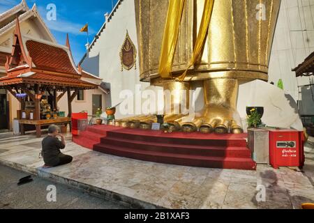 Eine Buddhistin betet vor den Füßen der 32 m hohen goldenen Buddha-Figur des Wat Indraviharn in Bangkok, Thailand Stockfoto