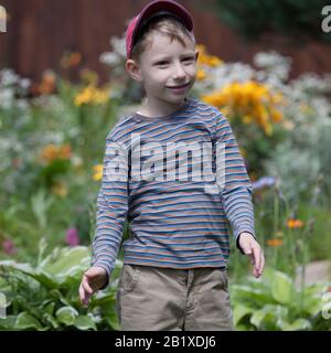 Niedlicher lustiger, fadenhaariger Junge spielt draußen. Stockfoto