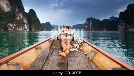 Junger Mann, der auf dem schwimmenden Boot schläft. Stockfoto