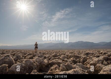 Eine alleinstehende Frau, die auf dem Devil's Golf Course eine große Salzpfanne im Tod Valley National Park in Kalifornien, USA steht. Stockfoto