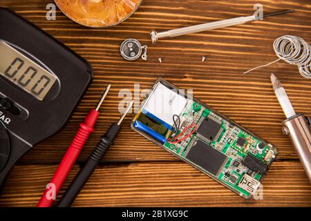 Set zum Löten von Draht und Schrumpflötschlauch mit Lötmittel neben Schraubendreher und Multimeter auf Holzhintergrund, Funk-Elektronik-Konzept Stockfoto