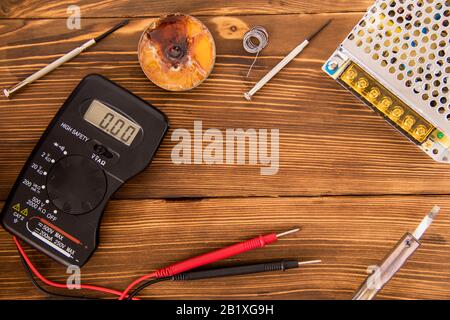 Set zum Löten von Draht und Schrumpflötschlauch mit Lötmittel neben Schraubendreher und Multimeter auf Holzhintergrund, Funk-Elektronik-Konzept Stockfoto