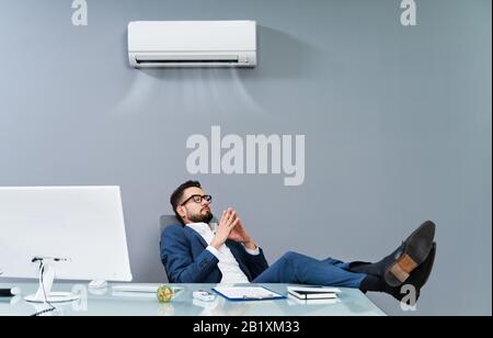 Entspannter Geschäftsmann, Der Die Klimaanlage Im Büro Kühlt Stockfoto