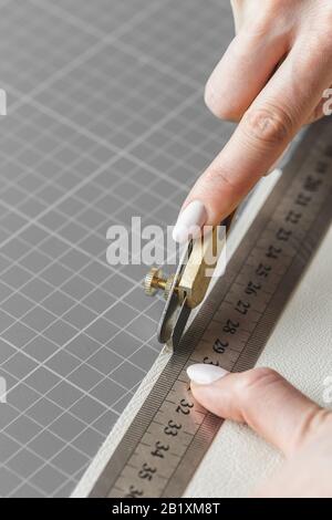 Handtaschendesignerin misst und schneidet Leder in einer Werkstatt Stockfoto