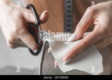 Damenhandtaschendesignerin misst Leder und schneidet Details in einem Werkstatt-Studio aus Stockfoto