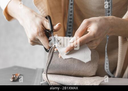 Damenhandtaschendesignerin misst Leder und schneidet Details in einem Werkstatt-Studio aus Stockfoto