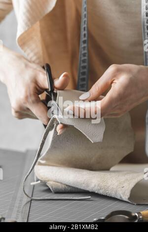 Damenhandtaschendesignerin misst Leder und schneidet Details in einem Werkstatt-Studio aus Stockfoto