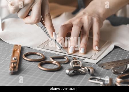 Damenhandtaschendesignerin misst Leder und schneidet Details in einem Werkstatt-Studio aus Stockfoto