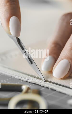 Damenhandtaschendesignerin misst Leder und schneidet Details in einem Werkstatt-Studio aus Stockfoto