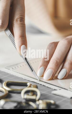 Damenhandtaschendesignerin misst Leder und schneidet Details in einem Werkstatt-Studio aus Stockfoto