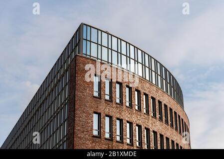 Hamburg, Deutschland - 4. August 2019: Außenansicht des modernen Bürogebäudes aus Backstein und Glas. Niedriger Blickwinkel gegen den Himmel Stockfoto