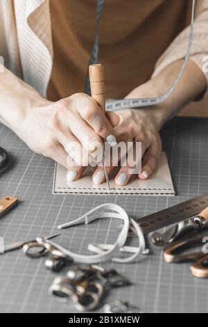 Handtaschendesignerin misst und schneidet Leder in einer Werkstatt Stockfoto