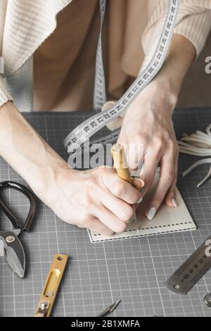 Handtaschendesignerin misst und schneidet Leder in einer Werkstatt Stockfoto