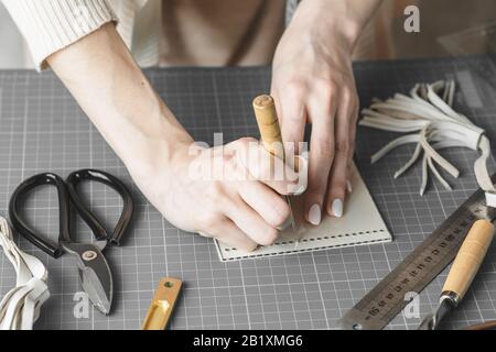 Handtaschendesignerin misst und schneidet Leder in einer Werkstatt Stockfoto