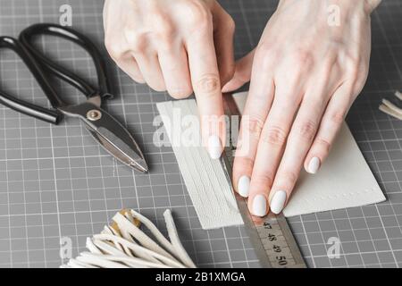 Handtaschendesignerin misst und schneidet Leder in einer Werkstatt Stockfoto