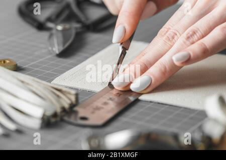 Handtaschendesignerin misst und schneidet Leder in einer Werkstatt Stockfoto