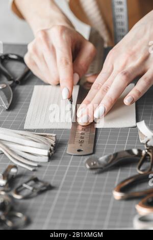 Handtaschendesignerin misst und schneidet Leder in einer Werkstatt Stockfoto