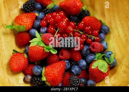 Frisches Beeren Obst in Holzschale enthält Erdbeere, Himbeere, blaue Beere, schwarze Beere usw. Stockfoto