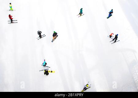 Draufsicht auf Skifahrer und Snowboarder, die auf dem Winterberg fahren. Stockfoto