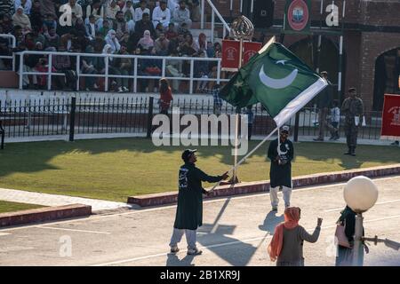 Wagah, Pakistan - Februar 8, 2020: Zwei pakistanische Männer winken Flaggen und überruchen die Menge für die Abschlussfeier der Grenze zu Wagah mit Indien Stockfoto