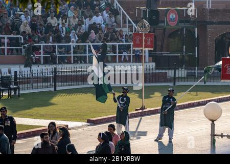 Wagah, Pakistan - Februar 8, 2020: Zwei pakistanische Männer winken Flaggen und überruchen die Menge für die Abschlussfeier der Grenze zu Wagah mit Indien Stockfoto