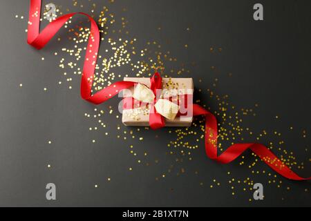 Geschenk- oder Präsentkiste und Goldsterne Konfetti auf schwarzem Tisch Draufsicht. Flat Lay Komposition zum Geburtstag, Muttertag, schwarzfreitagsverkauf, Weihnachten Stockfoto