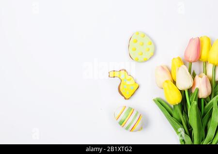 Hausgemachte Brötchenplätzchen aus Ostern mit Icing, verzierten Eiern und Tulpen auf weißem Hintergrund/Fröhliches osterkonzept. Kopierbereich, flaches Layout, Vorlage Stockfoto