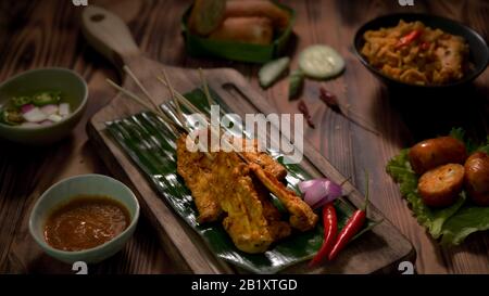 3/4-Schuss thailändisches traditionelles Straßenessen mit Schweinesatay mit Erdnusssauce und thailändischen Vorspeisen auf Holzschreibtisch Stockfoto