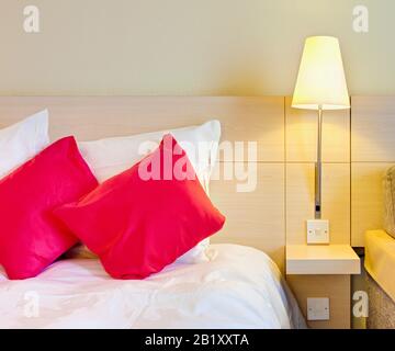 Einfaches Hotelzimmer, Bett mit Nachttisch in der Nähe, England Großbritannien Stockfoto