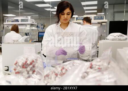 Der Produktionsleiter des Trainees verpackt Komponenten eines Extraktionskits zur Aufnahme von rna- und dna-Tupfer zur Identifizierung des Vorkommens von Coronavirus unter Stockfoto