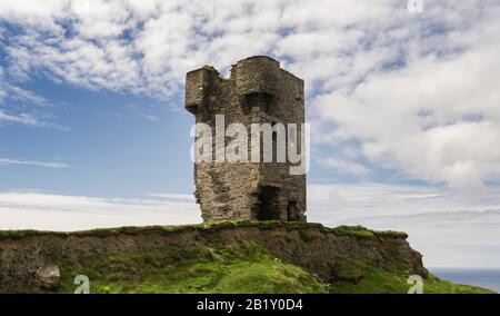 Ruinen eines alten Turms an den Klippen von Moher in Irland mit dem Meer im Hintergrund und bewölktem Himmel. Stockfoto