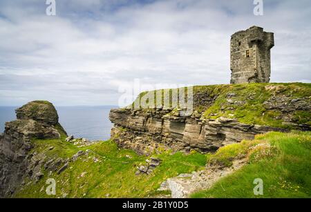 Ruinen eines alten Turms an den Klippen von Moher in Irland mit dem Meer im Hintergrund und bewölktem Himmel. Stockfoto
