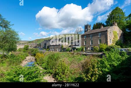 Sommerblick auf das Dorf Yorkshire Dales in Muker in Swaledale mit Häusern entlang der Straße, die durch das Dorf führt Stockfoto