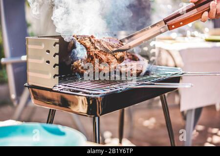 Küchenchef grillen T-Bone Steaks beim Barbecue-Dinner im Freien - Mann, der Fleisch für eine familiengrill-mahlzeit im Garten im Hinterhof kocht - Samme Lifestyle, Essen und su Stockfoto