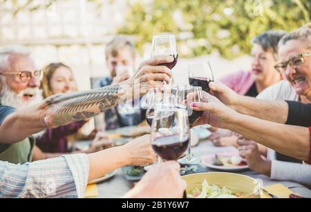 Fröhliche, trendige Familie jubelt mit Rotwein beim Barbecue-Dinner im Freien - Verschiedene Altersgruppen, die am sonntag Spaß haben - Essen, Geschmack und Sommerfrische Stockfoto